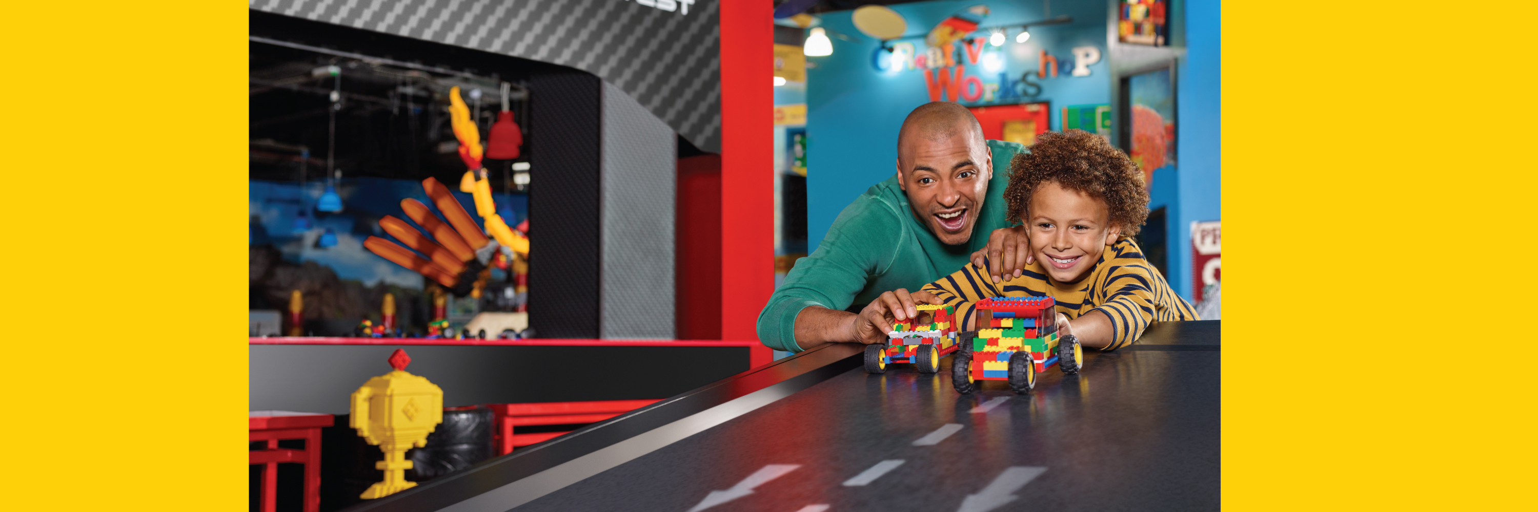 Excited boy and man racing colorful LEGO cars down a fun ramp at LEGOLAND Discovery Center Dallas, showcasing a vibrant play area filled with creativity and teamwork.