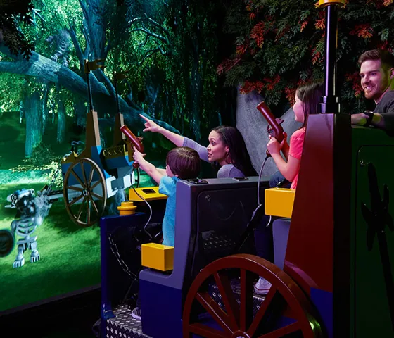 Family on LEGOLAND Discovery Center ride trying to hit targets with blunderbuss